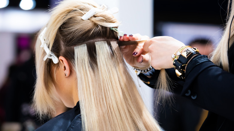 woman getting hair extensions inserted