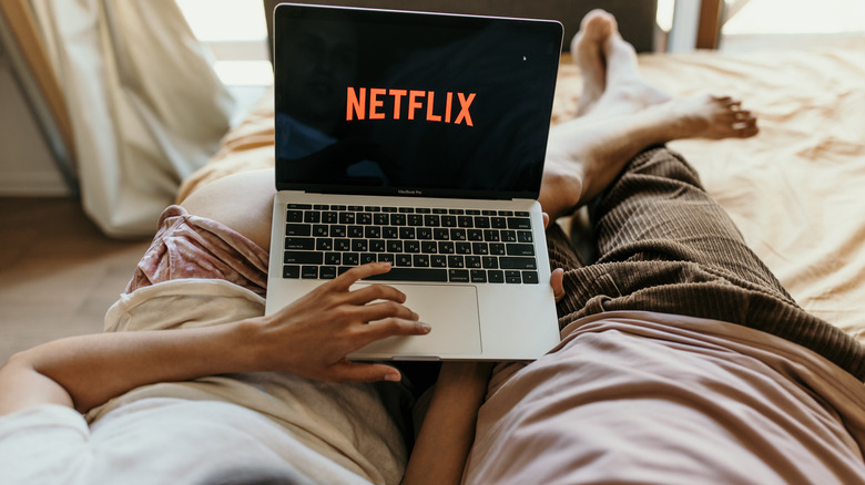 Computer on laps with the netflix logo on the screen