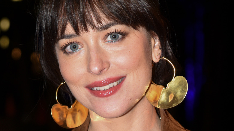 Dakota Johnson smiling, wearing earrings