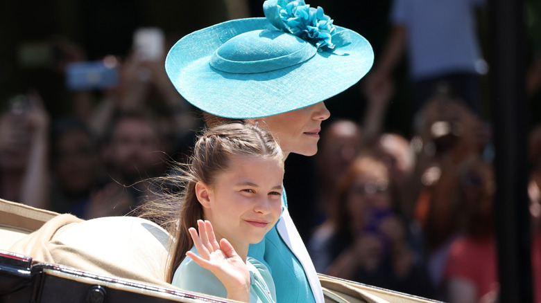 Princess Charlotte waving to a crowd, sitting next to mother, Princess Kate