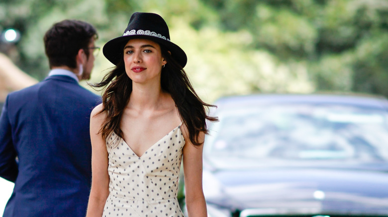 Margaret Qualley walking, wearing hat