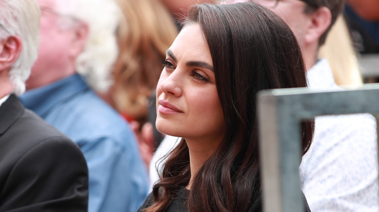 Mila Kunis sitting at an event