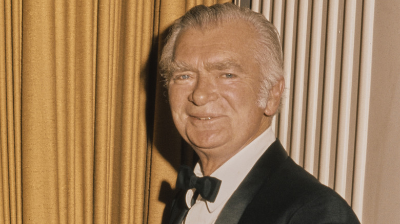 Buddy Ebsen wearing a suit and bow tie and standing in front of a curtain