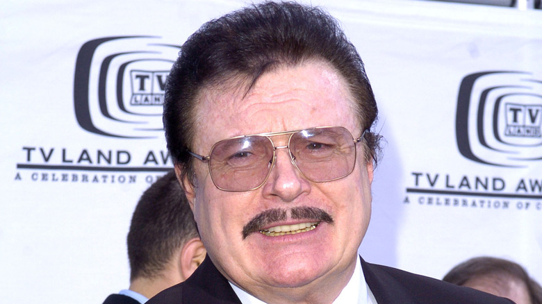 Max Baer Jr. wearing a suit and a pair of sunglasses