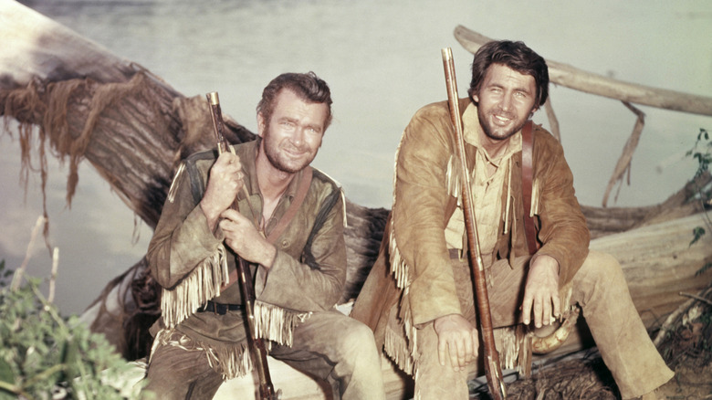 Buddy Ebsen and Fess Parker sitting on a log in Davy Crockett