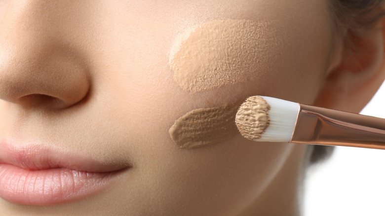 Woman using concealer and brush