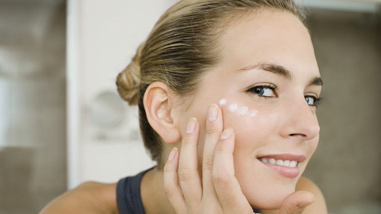 Woman putting moisturizer on her face