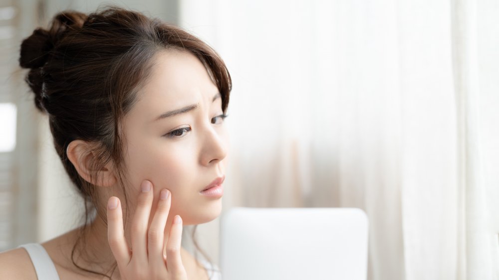 Woman looking in a mirror inspecting her skin 