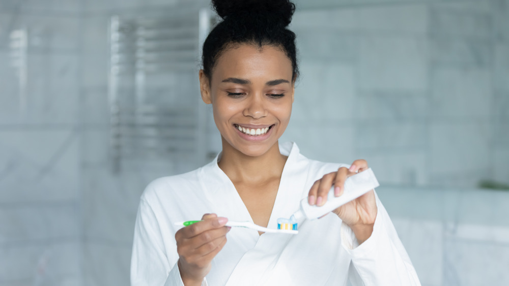 Woman applying toothpaste to toothbrush