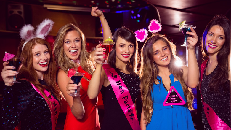 Bride and bridesmaids cheers with drinks in hand