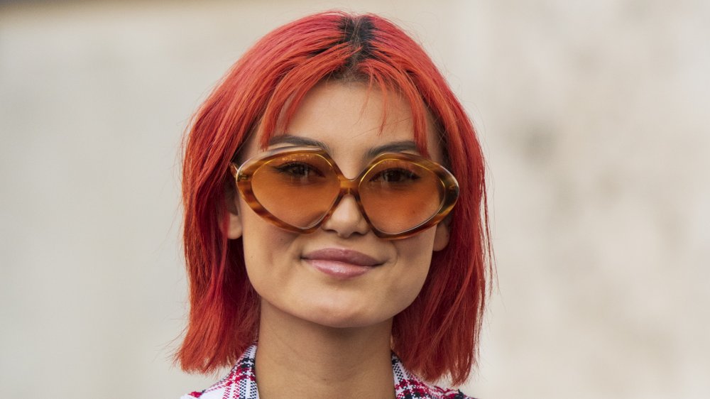 A woman with orange hair wearing sunglasses