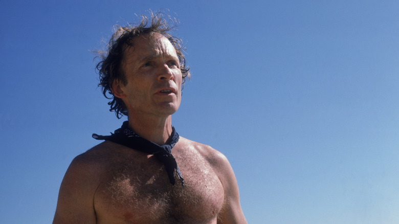 Shirtless Dick Cavett photographed against a blue sky