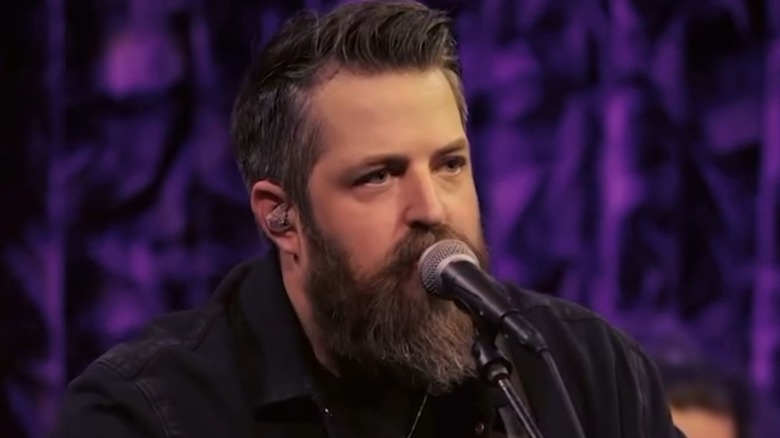 Bearded Lee DeWyze singing in front of a purple background
