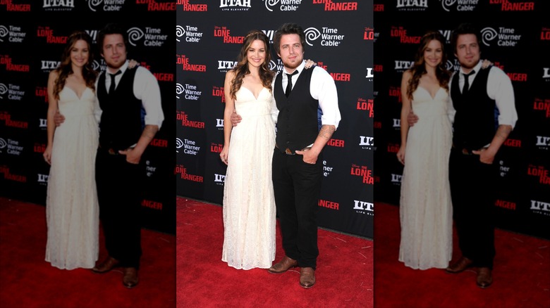 Jonna Walsh in a white dress and Lee DeWyze in a vest and tie, on a red carpet the year they got married