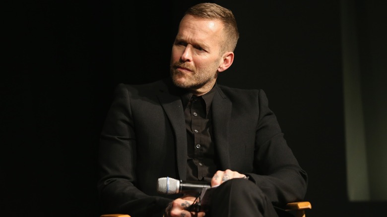 Bob Harper onstage holding a microphone in a black suit
