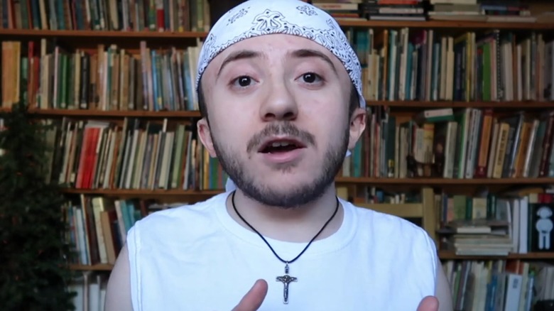 Atticus Shaffer talking in a video in his home in front of a bookshelf.