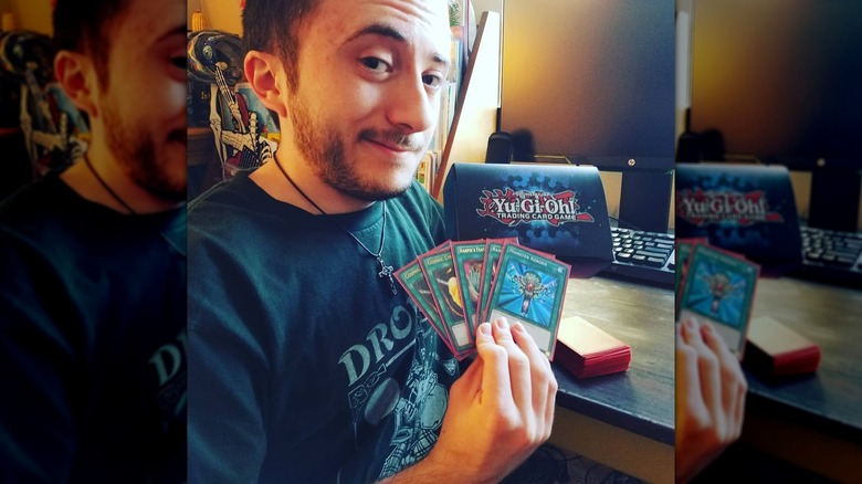 Atticus Shaffer smiling while holding Yu-Gi-Oh cards.