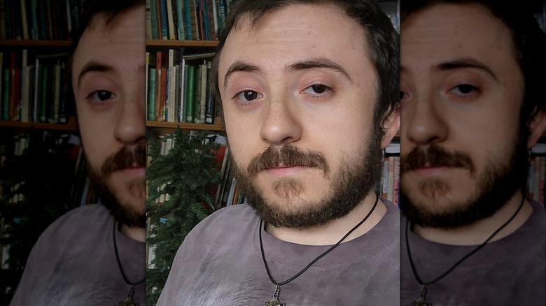 Atticus Shaffer taking a selfie in front of a bookshelf at his home.