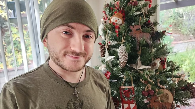 Atticus Shaffer smiling in front of a Christmas tree.