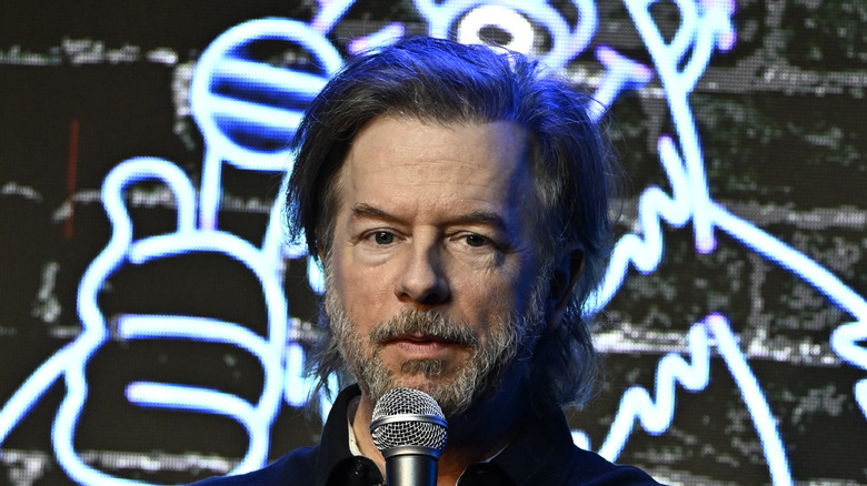 David Spade standing behind a microphone at The Ice House Comedy Club