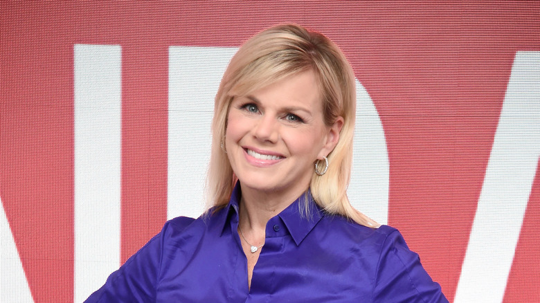 Gretchen Carlson posing in front of a white and red background