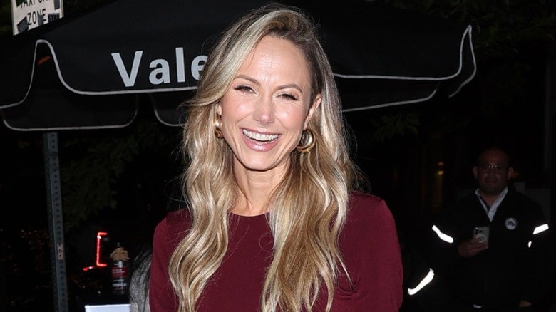 Stacy Keibler smiles while standing in front of a valet stand