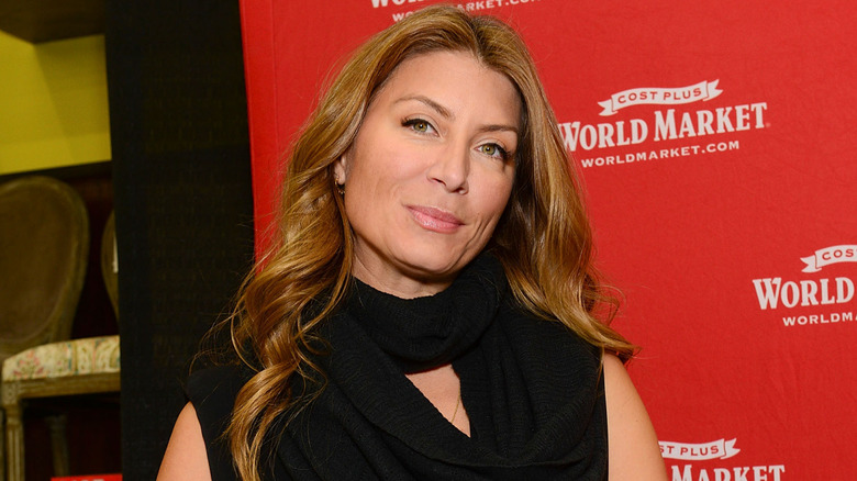 Genevieve Gorder poses in front of a red step and repeat wearing a black turtleneck