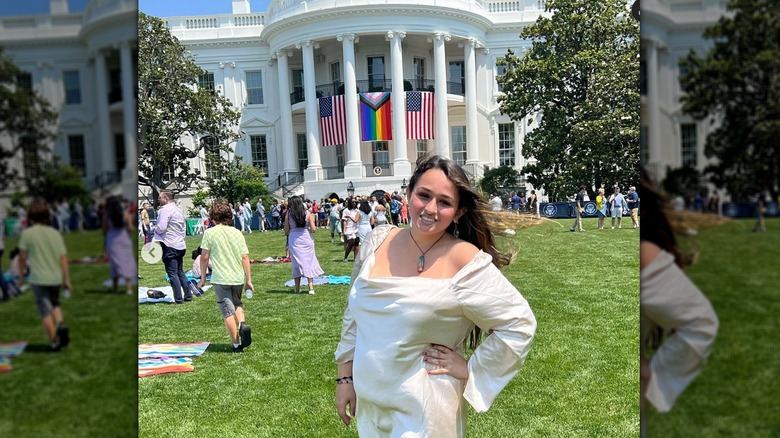 Jazz Jennings smiles with her hand on her hip in a white dress on the White House lawn during Pride.