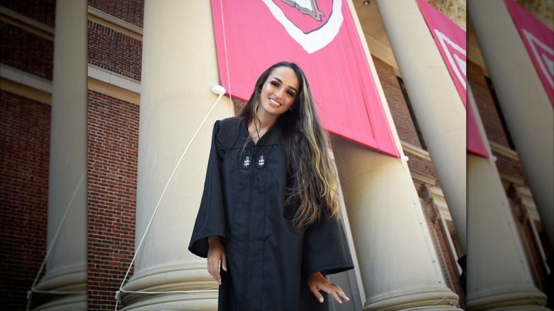 Jazz Jennings smiles in her graduation gown with a Harvard banner in the background.