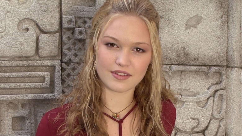 Julia Stiles in a red top against a stone wall in 2000