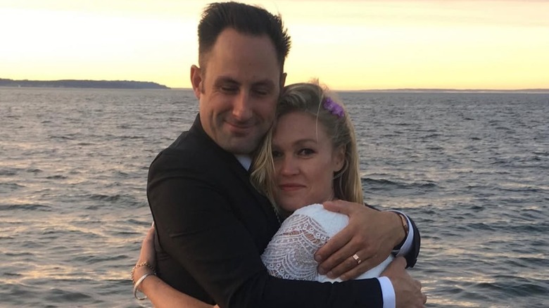 Preston Cook embracing Julia Stiles in her wedding dresson a beach