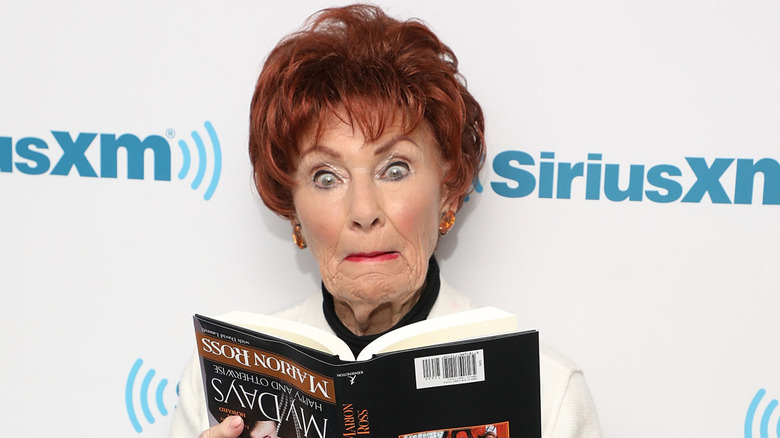 Marion Ross making a silly face and holding her book upside down