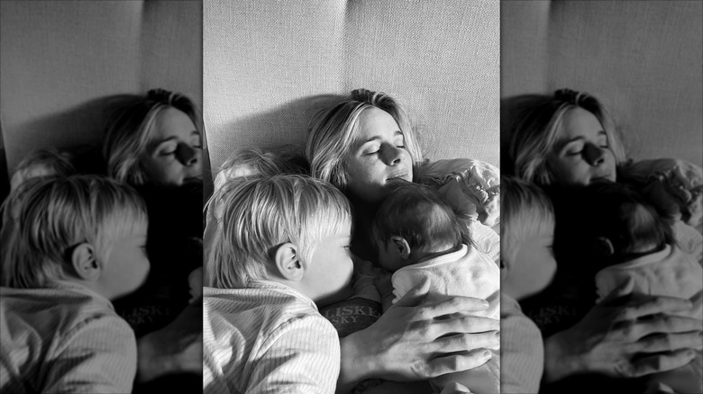 A black and white photo of Cressida Bonas with her two children laying on her chest
