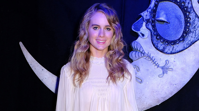Cressida Bonas smiling in a dark room against a big hanging moon decoration