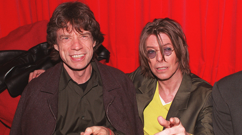Mick Jagger and David Bowie in front of a red curtain