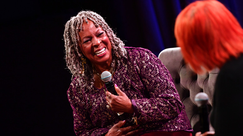 Martha Reeves sitting on a couch and holding a microphone