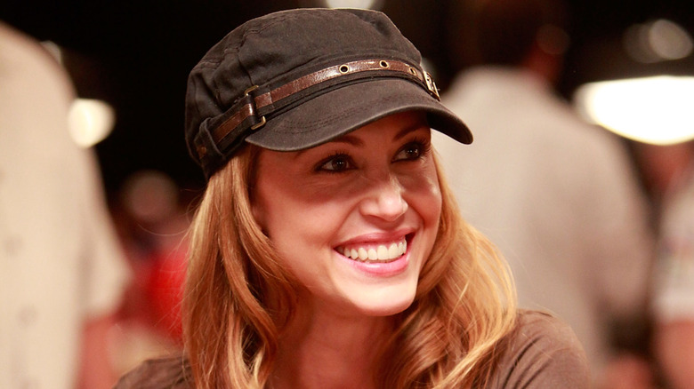Shannon Elizabeth smiles while wearing a brown hat