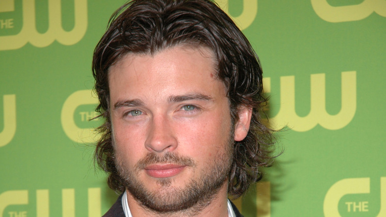Close-up of Tom Welling in front of a green CW banner