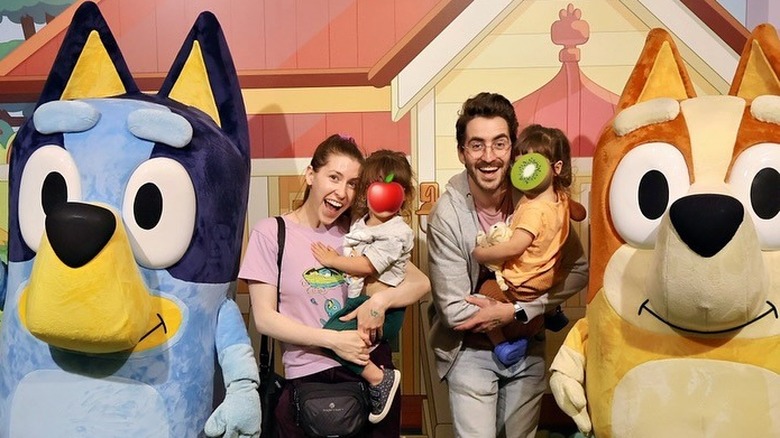 Eden Sher and Nick Cron-DeVico posing with their twins and costumed "Bluey" characters