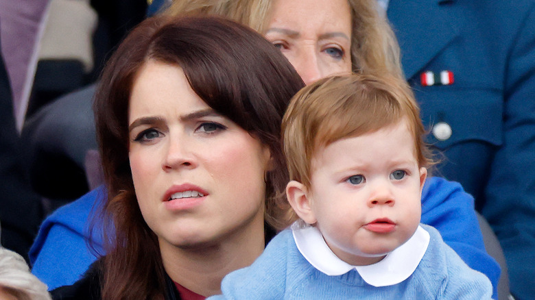 Princess Eugenie holding one of her sons who is wearing a blue sweater