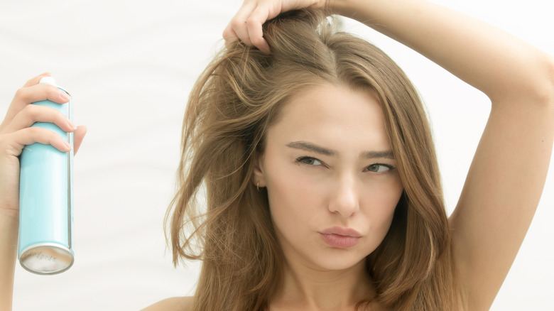 Woman spraying product onto hair 