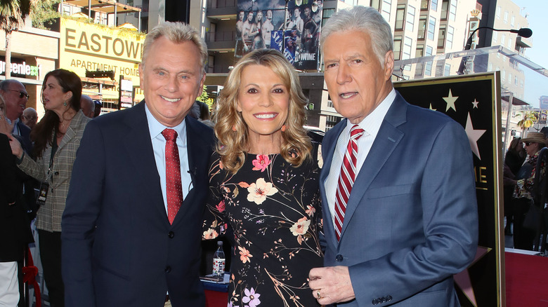Vanna White, Pat Sajak, and Alex Trebek pose together on the red carpet outside in Hollywood