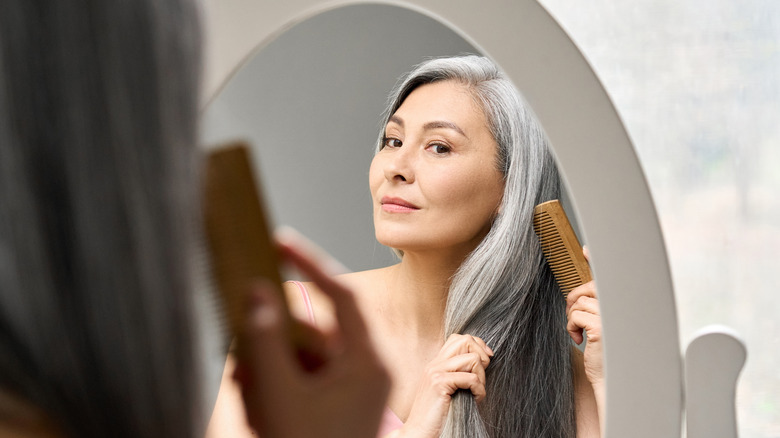 Beautiful woman combing her gray hair