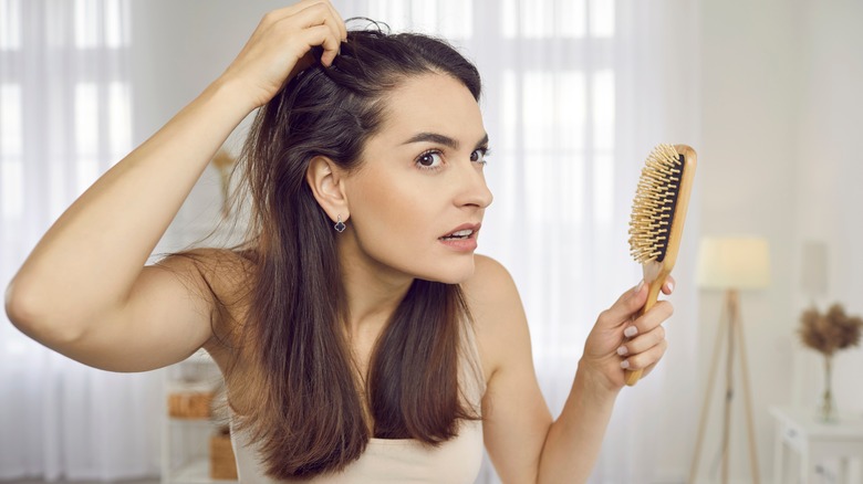 Woman examining scalp in mirror
