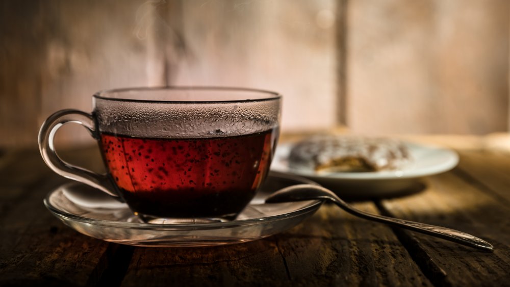 A cup of black tea on a saucer with a spoon