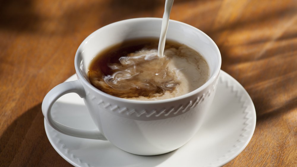 Creamer being poured into a cup of coffee