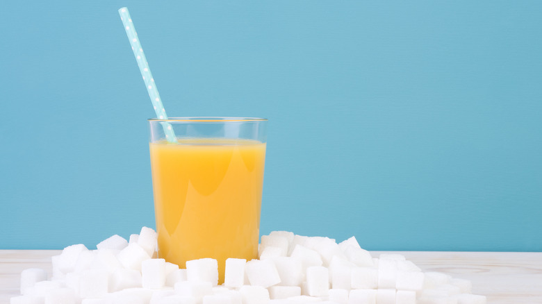 a glass of orange juice with sugar cubes around it