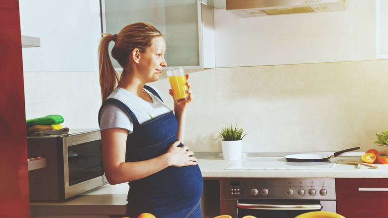 a pregnant woman drinking orange juice