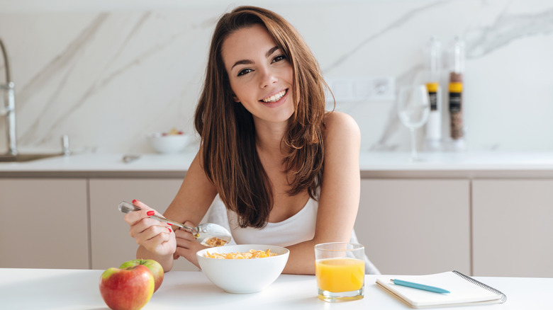 a woman eating breakfast with orange juice