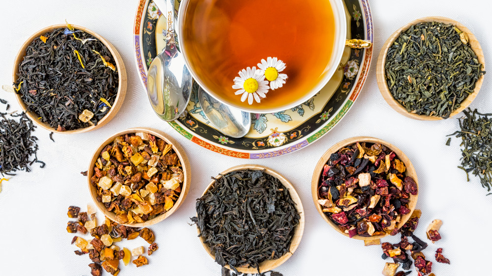 Cup of tea surrounded by dry tea leaves